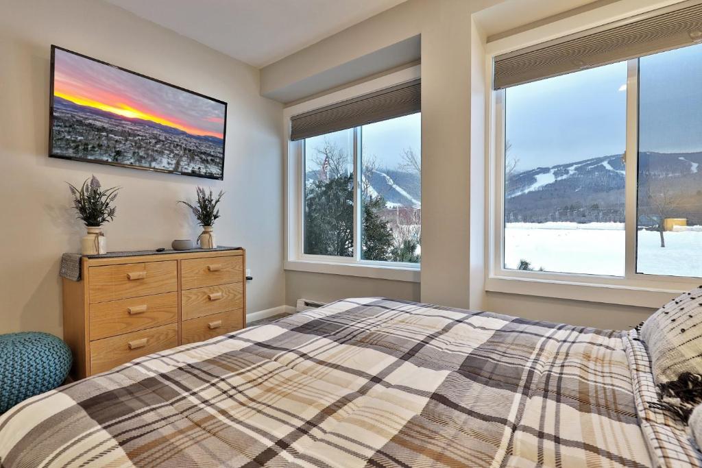 キリングトンにあるMountain Green 3C16 - Renovated 2BR-2BA With Mountain Views, Hot Tub, Pool, Shuttle, Gymのベッドと2つの窓がある寝室