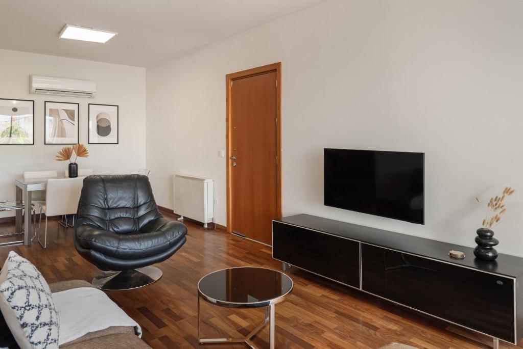 a living room with a black leather chair and a flat screen tv at Phaedrus Living Evergreen Nicosia City Residence in Nicosia