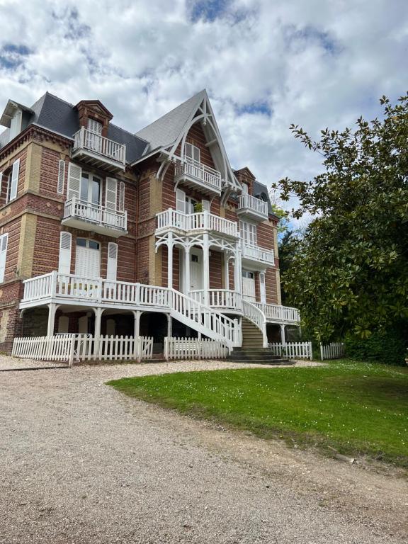 une grande maison en briques avec une clôture blanche devant elle dans l'établissement La mer avec un petit jardin, à Villers-sur-Mer