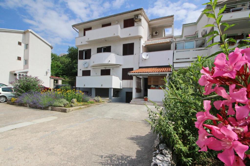 Un edificio con flores rosas en el frente. en Apartments Karamarko, en Baška