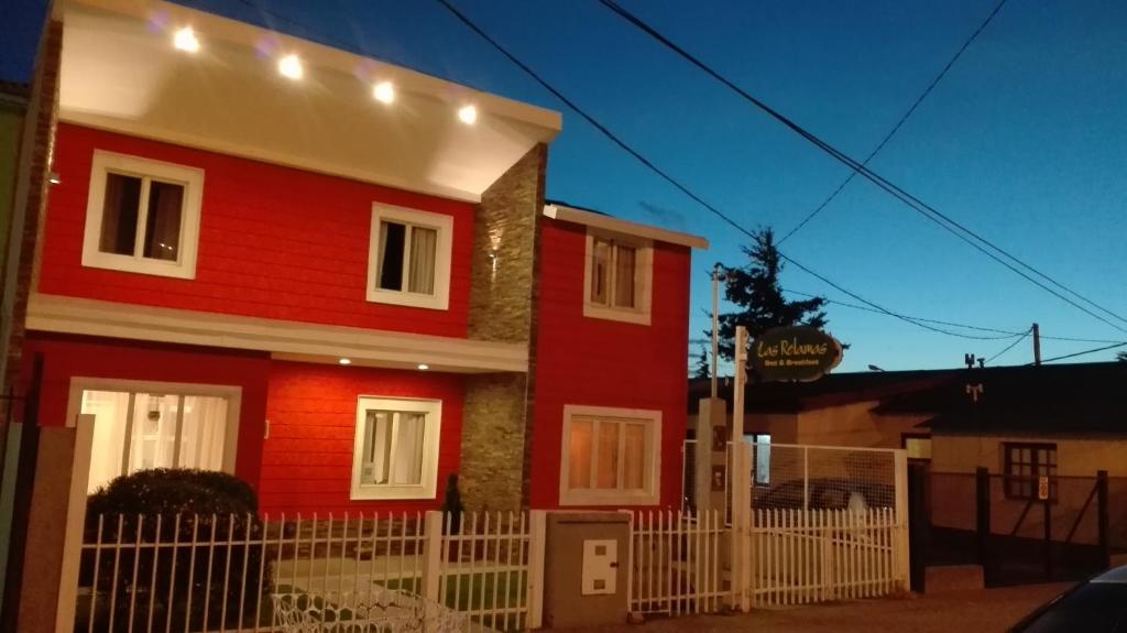 una casa roja con una valla blanca delante de ella en Las Retamas B&B en Ushuaia