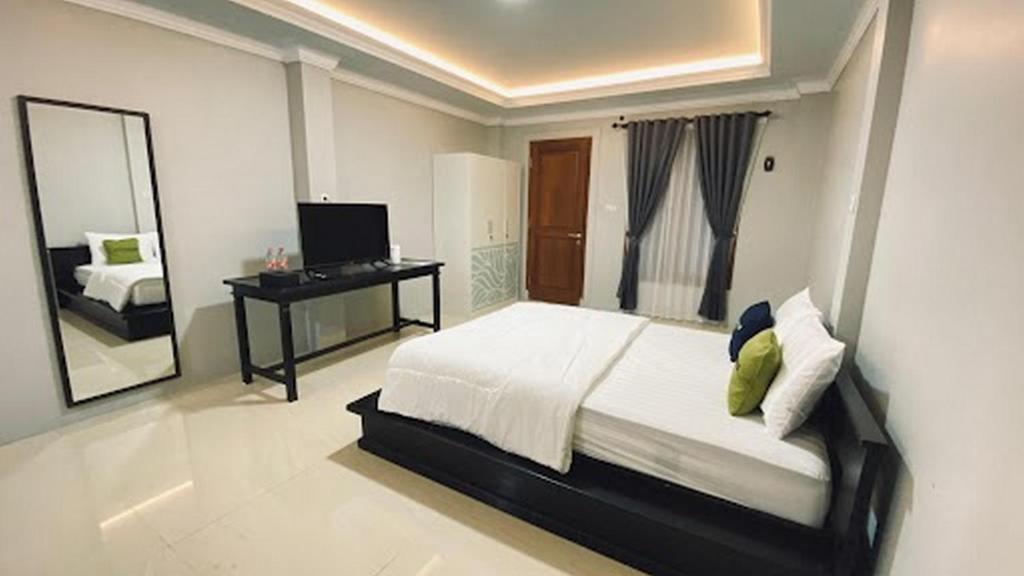 a bedroom with a bed and a desk and a mirror at Urbanview TWH Costel near Stadion Maguwoharjo Yogyakarta in Yogyakarta