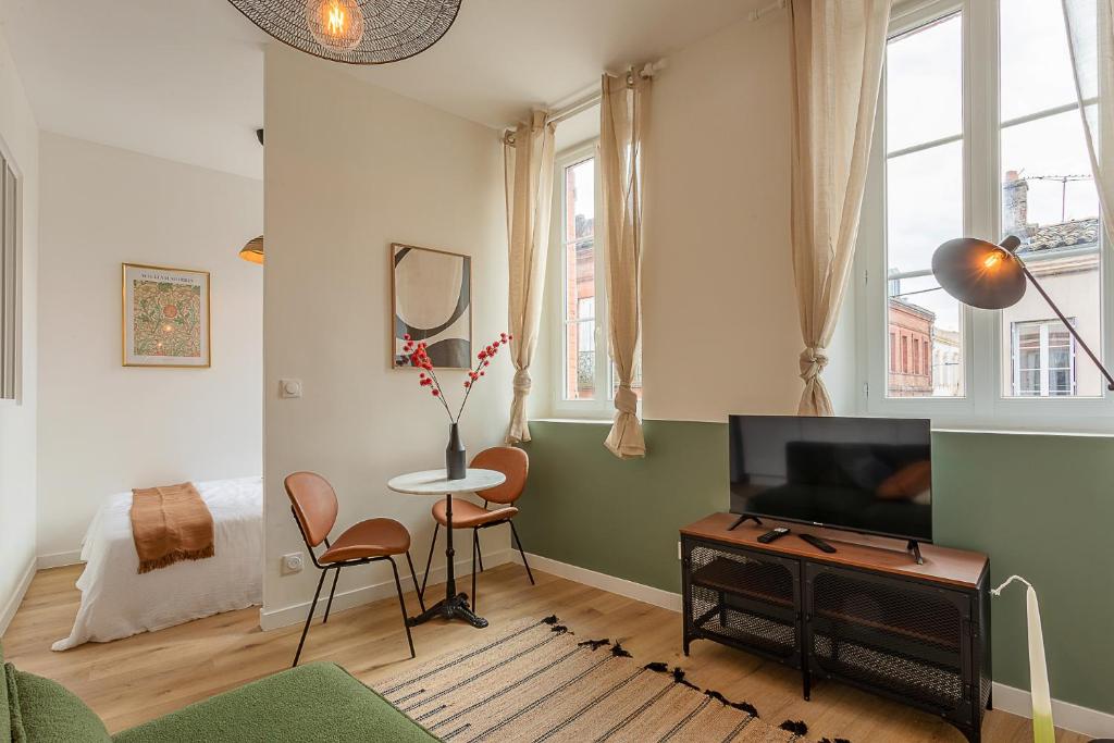 un salon avec une télévision, une table et des chaises dans l'établissement Le Tisserand - Appartement Cosy proche de la Gare, à Toulouse