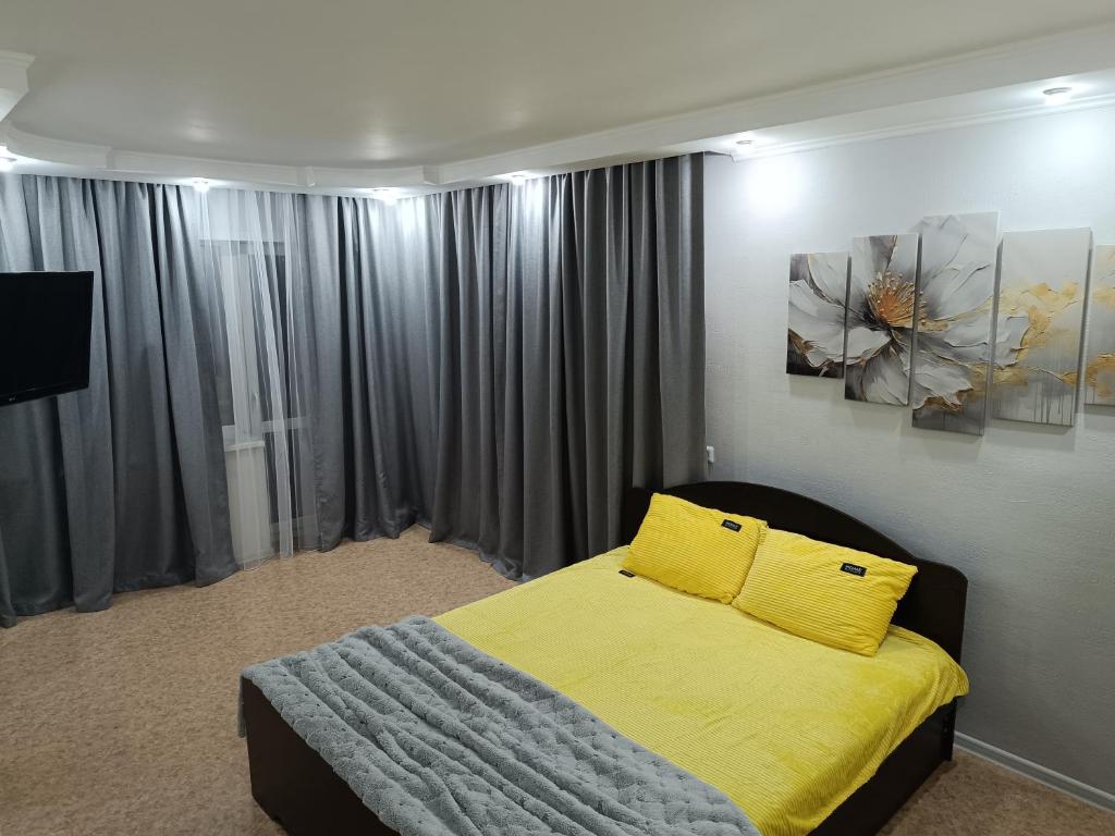 a bedroom with a bed with a yellow blanket at Современные апартаменты в центре города in Ustʼ-Kamenogorsk