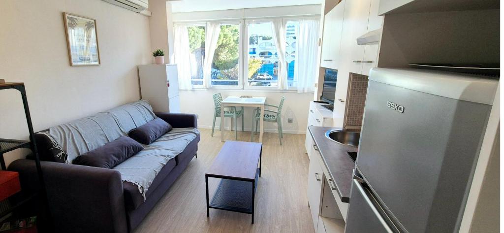 un salon avec un canapé et une cuisine dans l'établissement Le beaulieu design cosy clim centre ville, à La Grande Motte