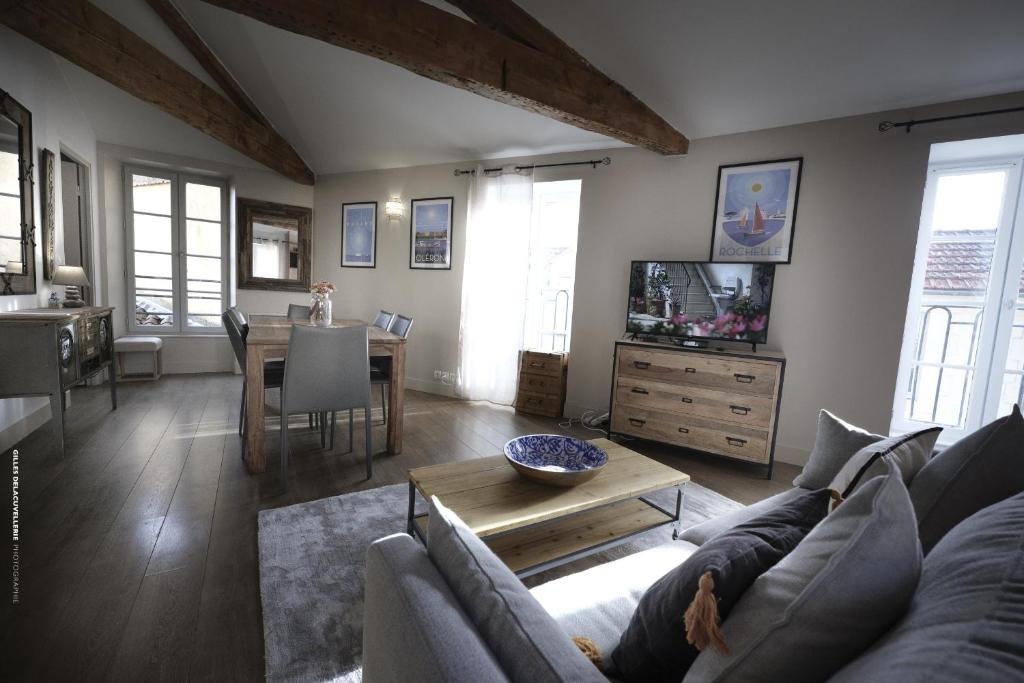 un salon avec un canapé, une télévision et une table dans l'établissement Appartement de charme au Marche avec parking, à La Rochelle