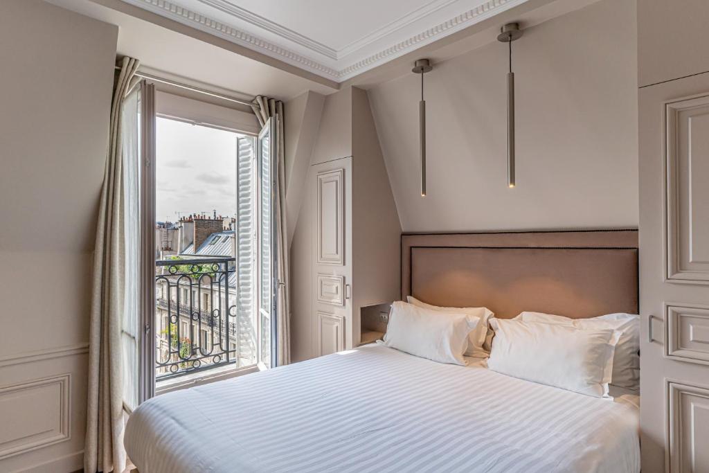 a bedroom with a bed and a large window at Hôtel Perreyve - Jardin du Luxembourg in Paris