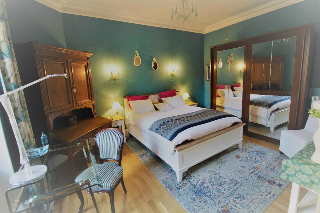 une chambre avec un lit, une chaise et un miroir dans l'établissement AME Mombrun, à Vichy