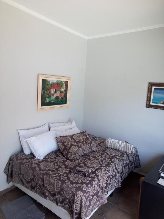a bedroom with a bed in a white room at Pousada Muzeli in Itanhaém