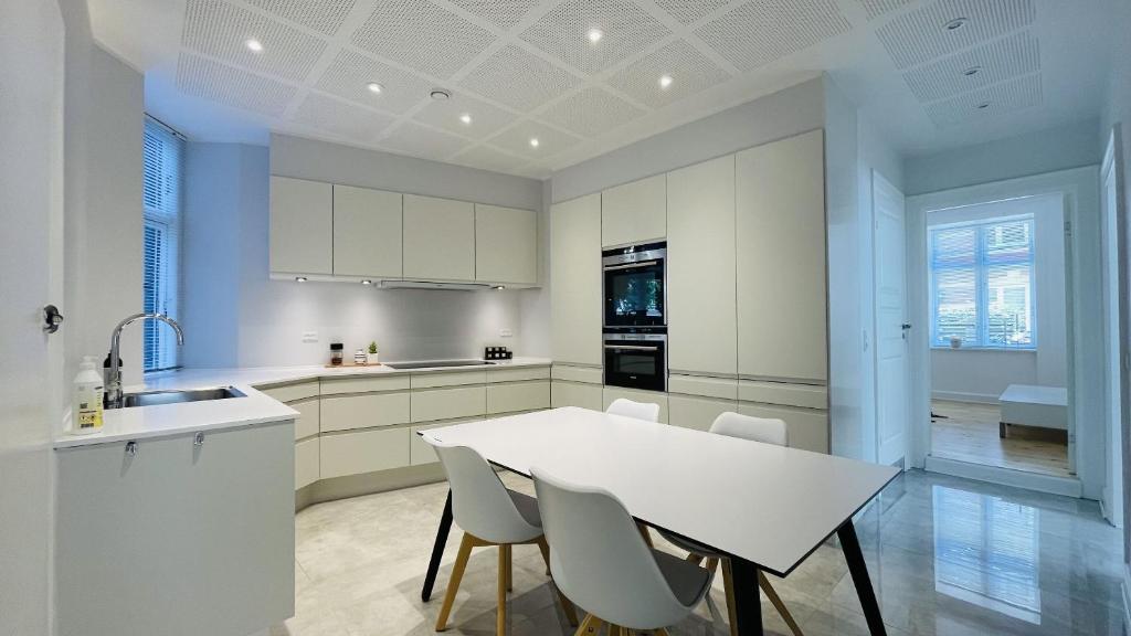a white kitchen with a white table and chairs at ApartmentInCopenhagen Apartment 1501 in Copenhagen