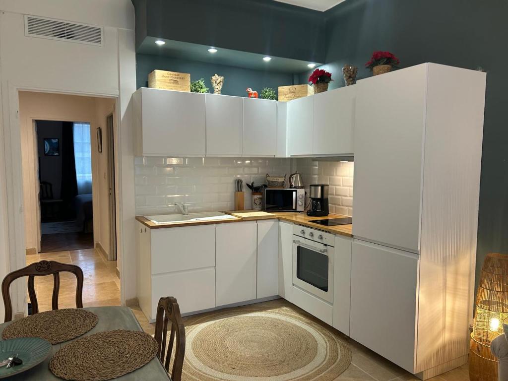 une cuisine avec des armoires blanches et une table et une salle à manger dans l'établissement Joli et lumineux appartement proche mer et centre ville Nice, à Nice