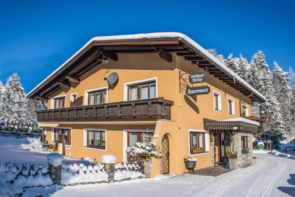 żółty dom w śniegu z drzewami w obiekcie Landhaus Relly w mieście Seefeld in Tirol