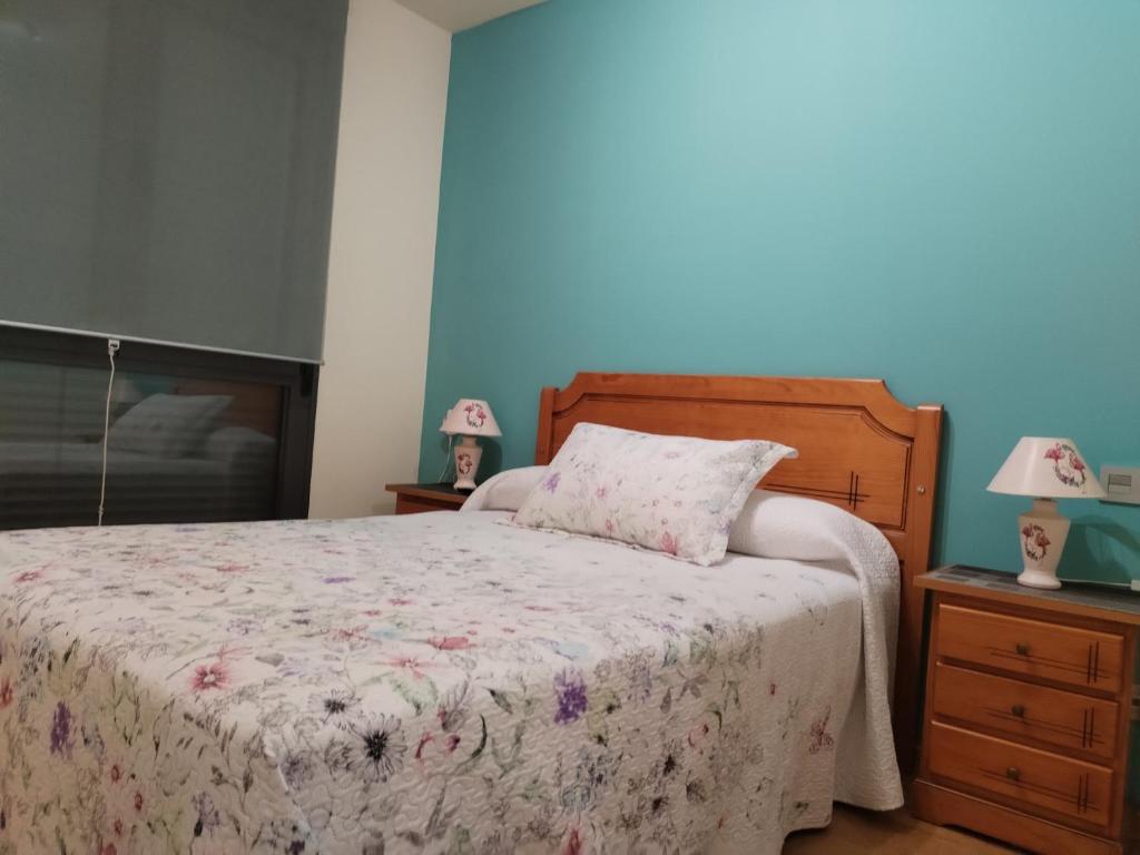a bedroom with a bed and two lamps on dressers at Apartamentos Chevere Azul con Garaje in Oviedo