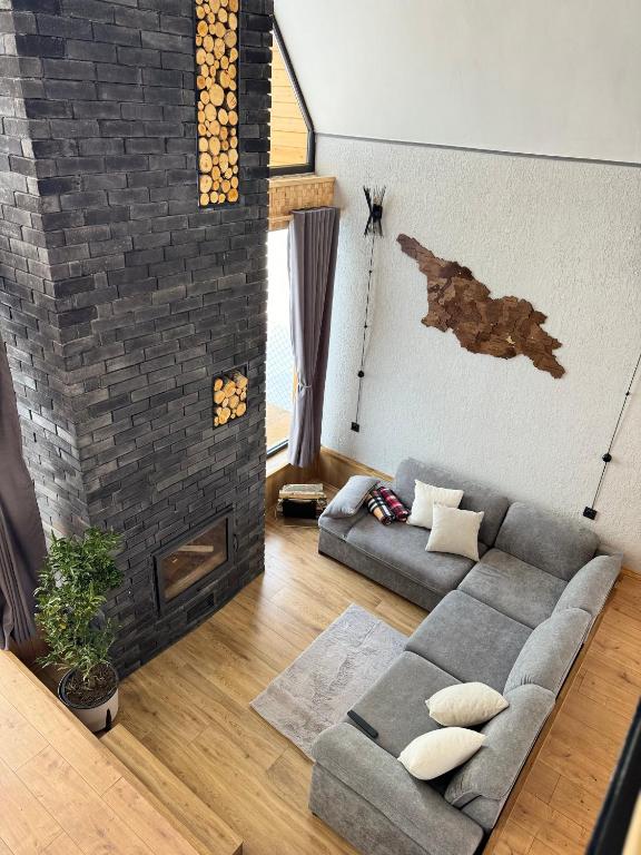 a living room with a couch and a brick wall at Cottage River Sound in Kazbegi