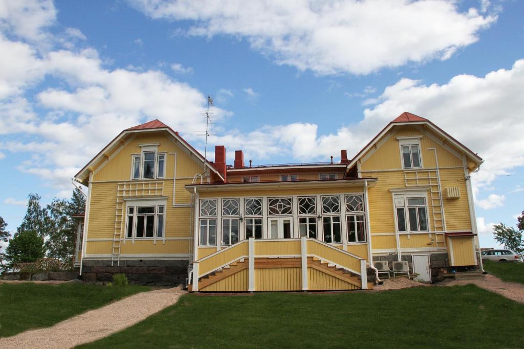 una gran casa amarilla con un gran patio delantero en Woikoski Feeling - Kirjokiven Kartano, en Joutsenlahti