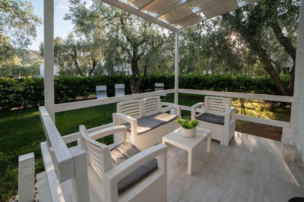 a porch with white chairs and a pergola at saracena Holiday Home with Private Beach and Swimming Pool in Mattinata