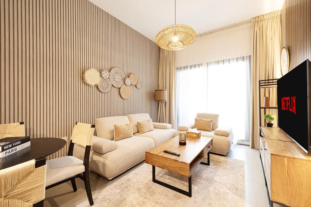 una sala de estar con un sofá y una mesa en 1BHK Poolview Apartment With Balcony - Timber Retreat, en Sharjah