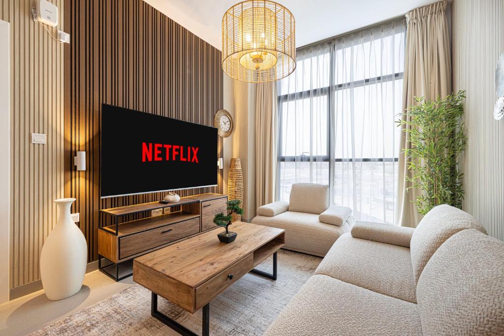 Una sala de estar con televisión y un sofá. en Luxury 1-Bedroom Apartment with Hall in Mamsha, en Sharjah