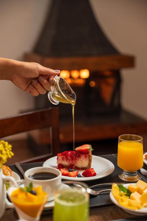 a person is pouring syrup onto a plate of food at Pousada Grandchamp - Campos do Jordao in Campos do Jordão