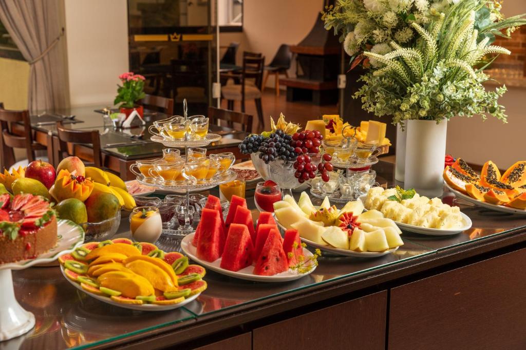 a buffet with many plates of fruit on a table at Pousada Grandchamp - Campos do Jordao in Campos do Jordão