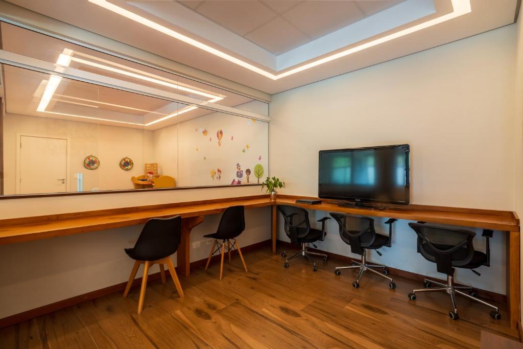 a room with a desk with chairs and a television at Pousada Grandchamp - Campos do Jordao in Campos do Jordão