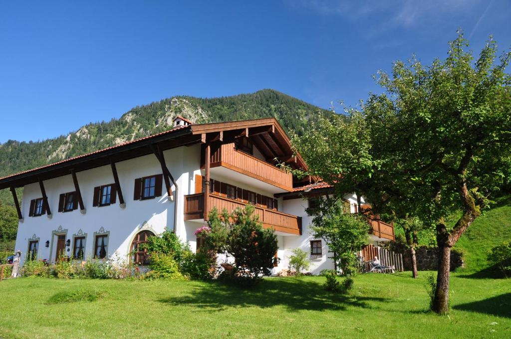 ein weißes Gebäude mit Holzbalkonen und einem Baum in der Unterkunft Gästehaus Gritscher in Josefsthal