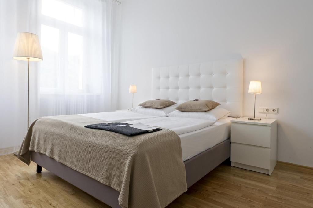 a white bedroom with a large white bed with two lamps at Burgblickhotel in Bernkastel-Kues