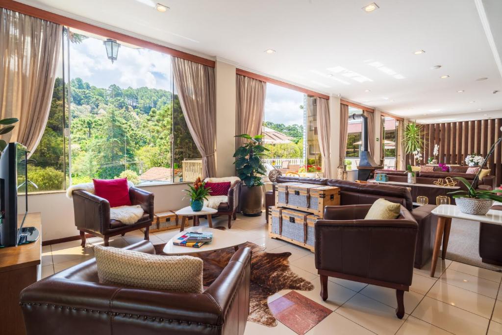 a living room with leather furniture and large windows at Pousada Grandchamp - Campos do Jordao in Campos do Jordão
