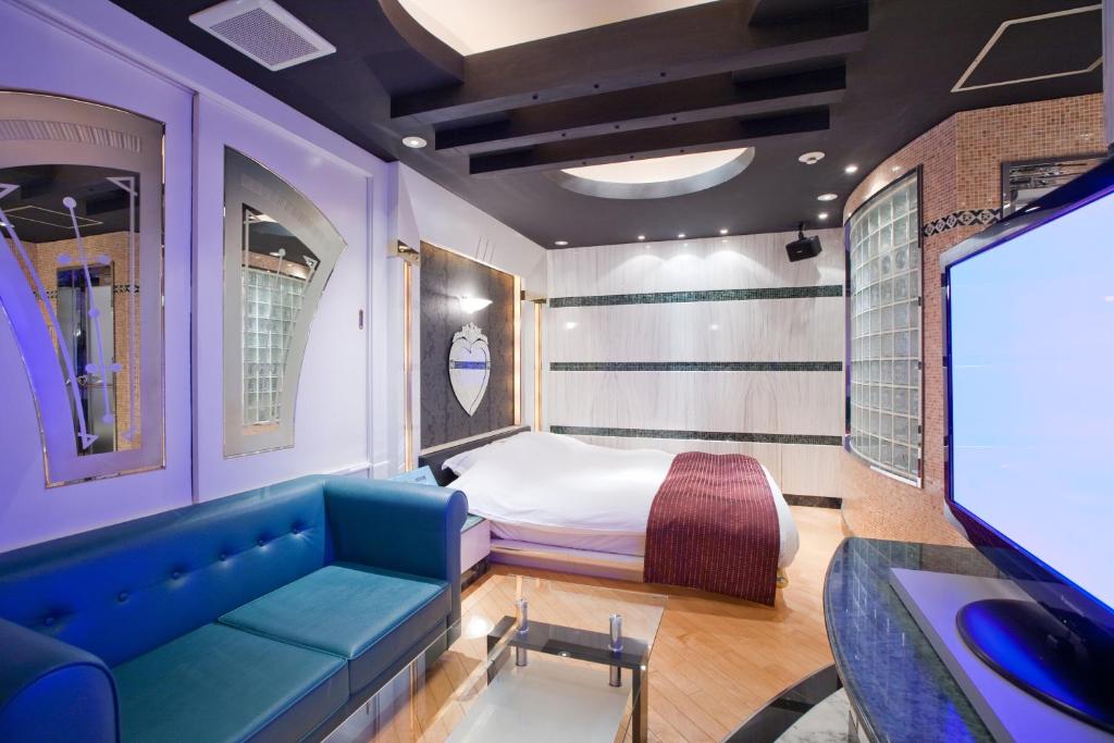a room with a bed and a couch and a tv at HOTEL & SPA J-MEX Shinjuku Kabukicho (Adult Only) in Tokyo