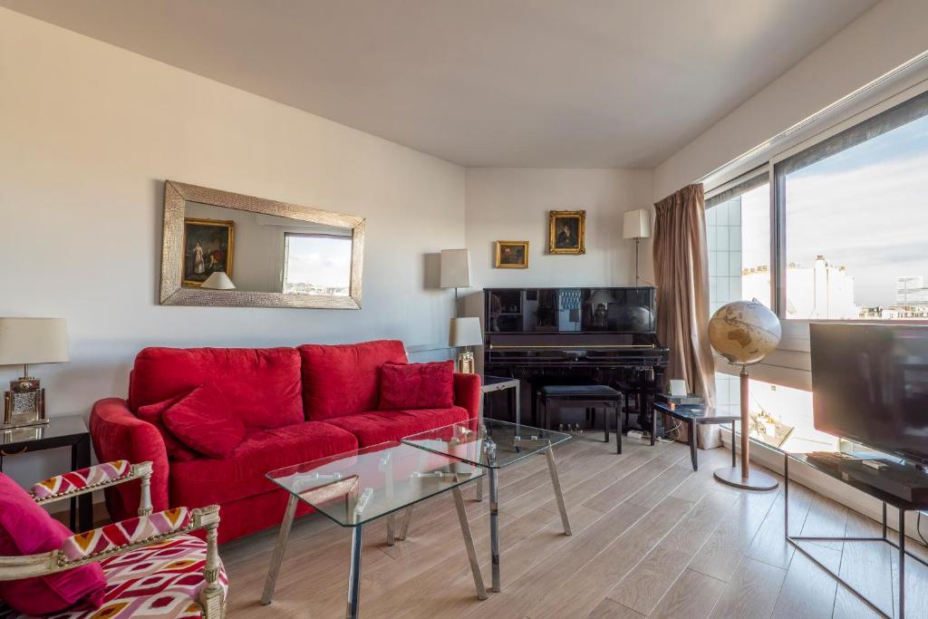 - un salon avec un canapé rouge et un piano dans l'établissement Veeve - Panoramic Views from the 17th, à Paris