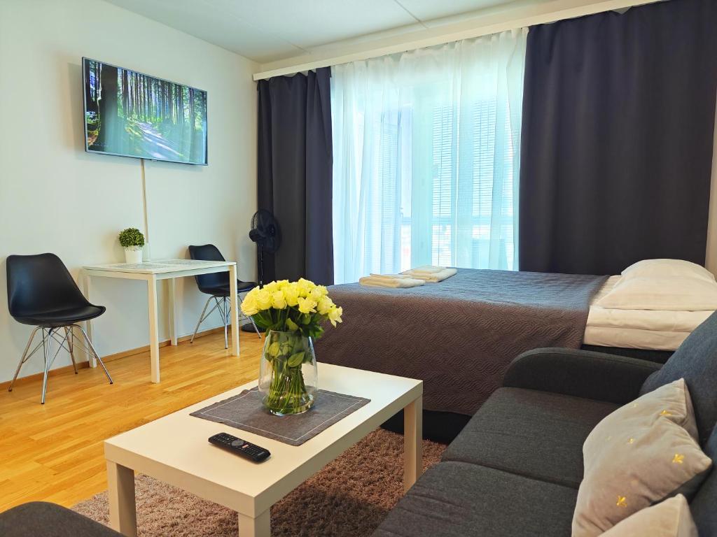 a room with a bed and a vase of flowers on a table at Top location IICenter IIParking in Oulu