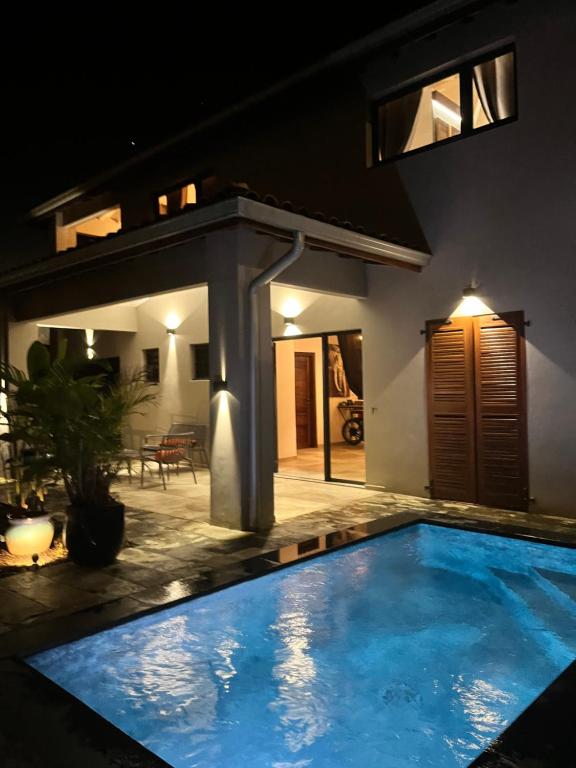 a swimming pool in front of a house at night at Villa passion vanille in Les Trois-Îlets