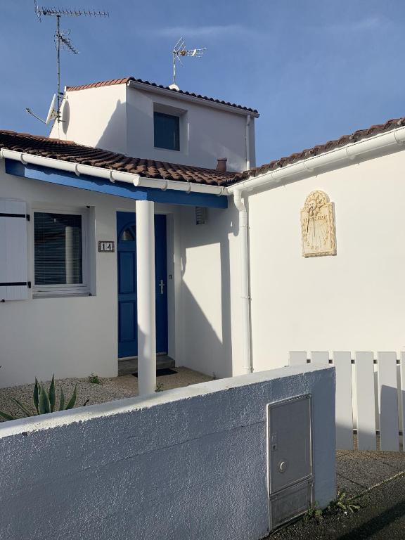 une maison blanche avec une porte bleue et une clôture dans l'établissement Les Clarisses, à Saint-Gilles-Croix-de-Vie