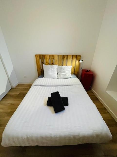 - un lit blanc avec un objet noir sur le lit dans l'établissement Le Gambetta - 2 voyageurs - Wifi, au Mans