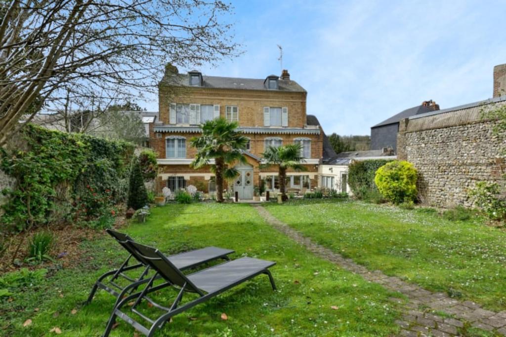 un banc assis dans l'herbe devant une maison dans l'établissement Villa Jane'Laur Magnificent mansion with garden 11 P, à Honfleur