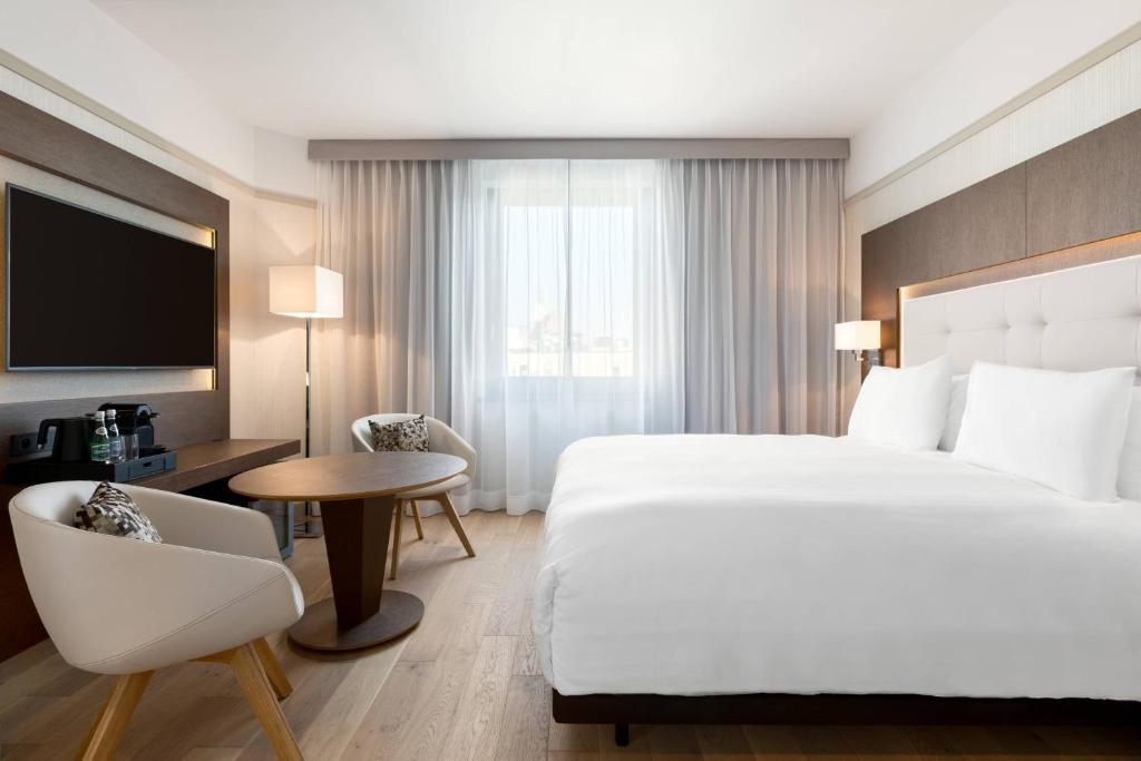 a hotel room with a bed and a desk and a tv at AC Hotel by Marriott Wroclaw in Wrocław