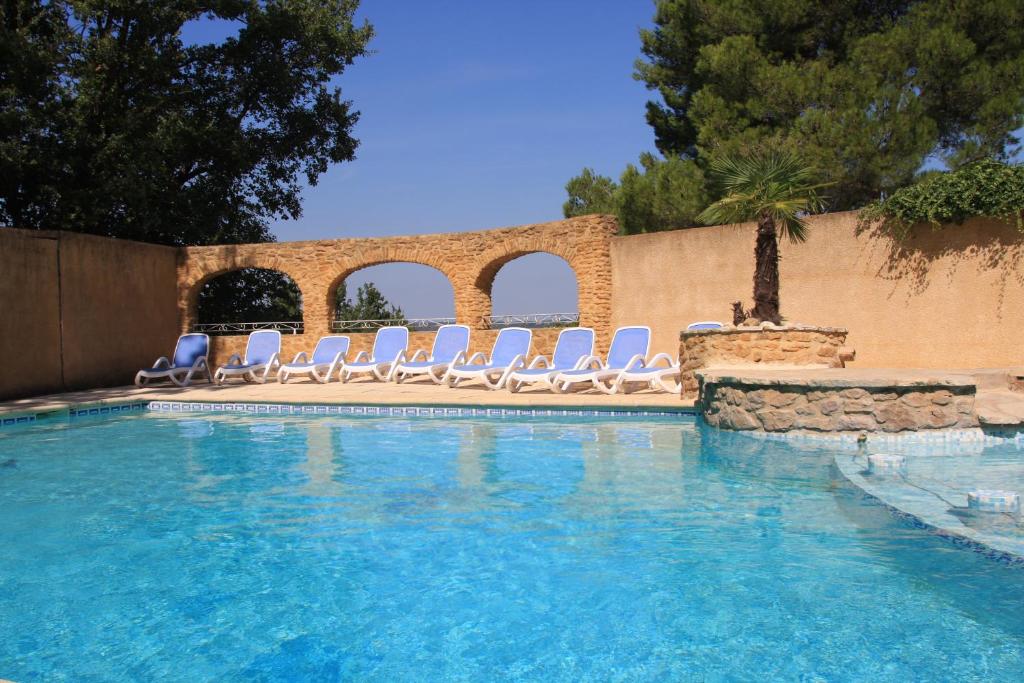 a swimming pool with lounge chairs and a wall at Gîtes La Pousterle De Sabran in Sabran