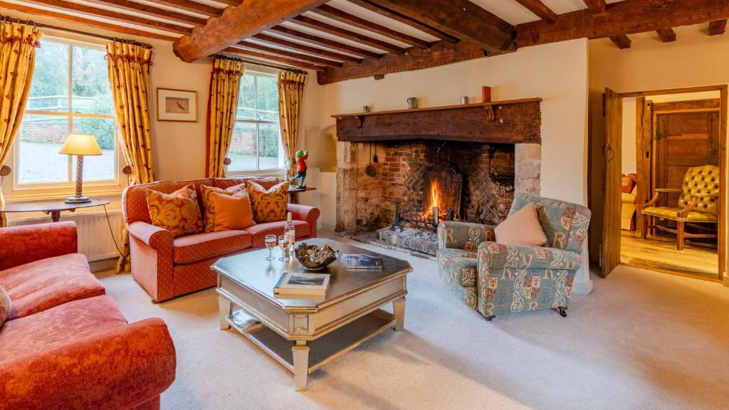 a living room with a fireplace and red furniture at Coppice House in Ashton under Hill