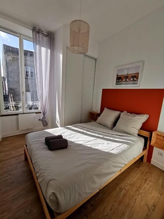 un grand lit dans une chambre avec une grande fenêtre dans l'établissement L'Orangeade, à Cognac