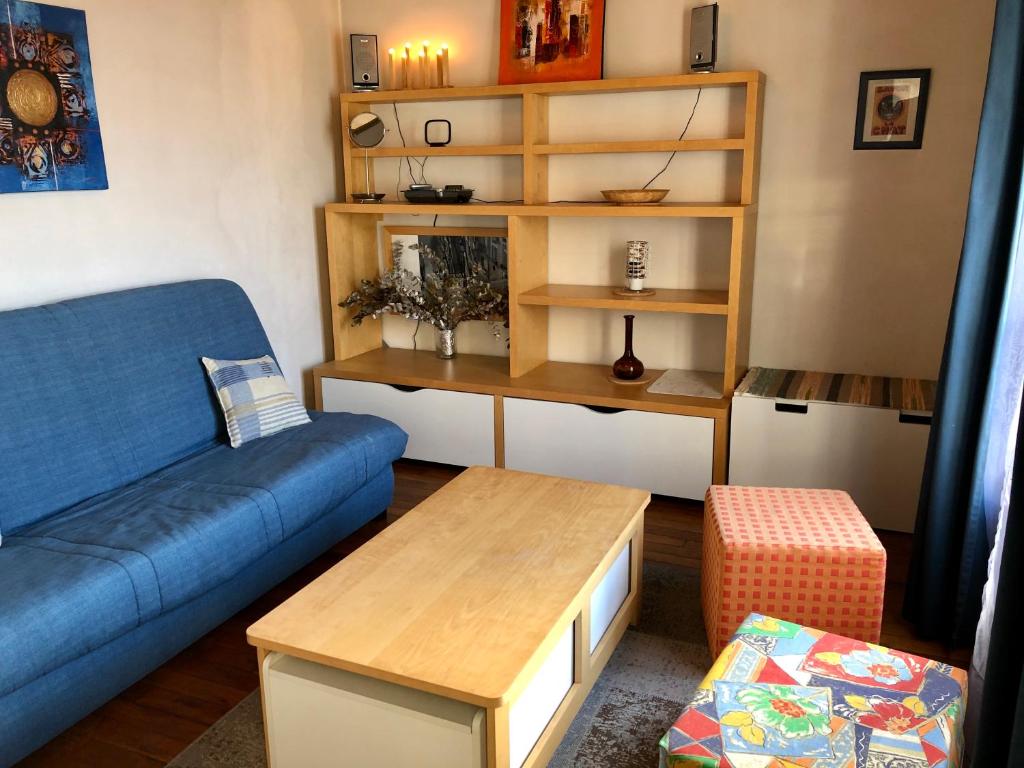 un salon avec un canapé bleu et une table dans l'établissement Appartement calme Paris XXeme, à Paris