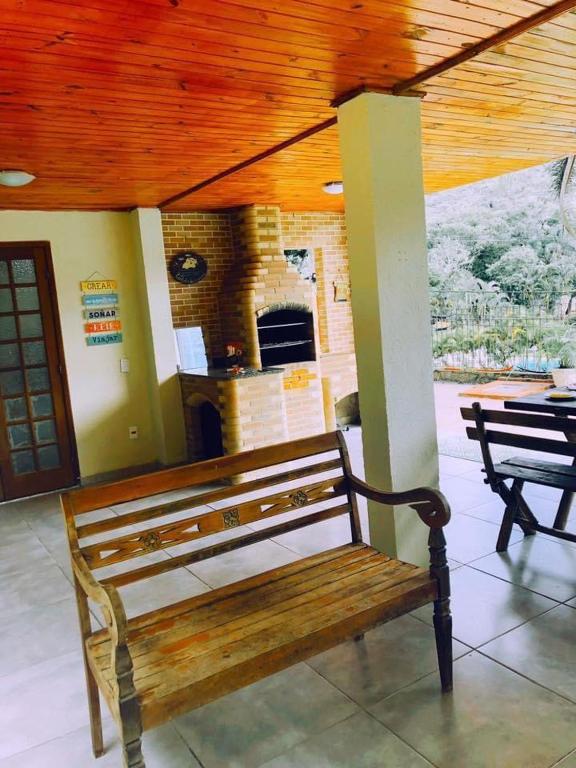 a wooden bench in a building with a fireplace at Sobrado em Javary - 1 km do Lago in Miguel Pereira
