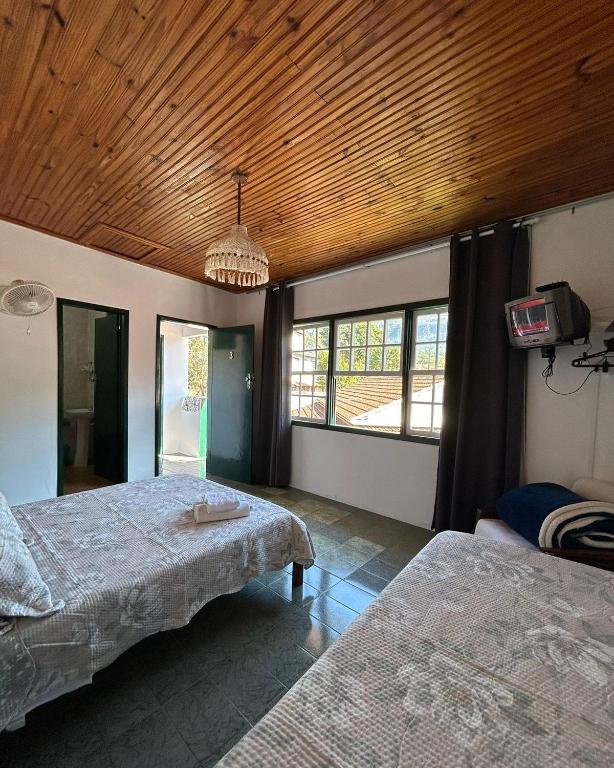 a bedroom with two beds and a wooden ceiling at Pousada Sierra in Tiradentes