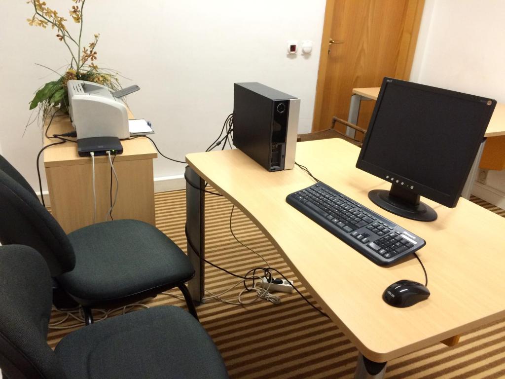 a desk with a computer monitor and a keyboard and mouse at Riviera Hotel in Carcavelos