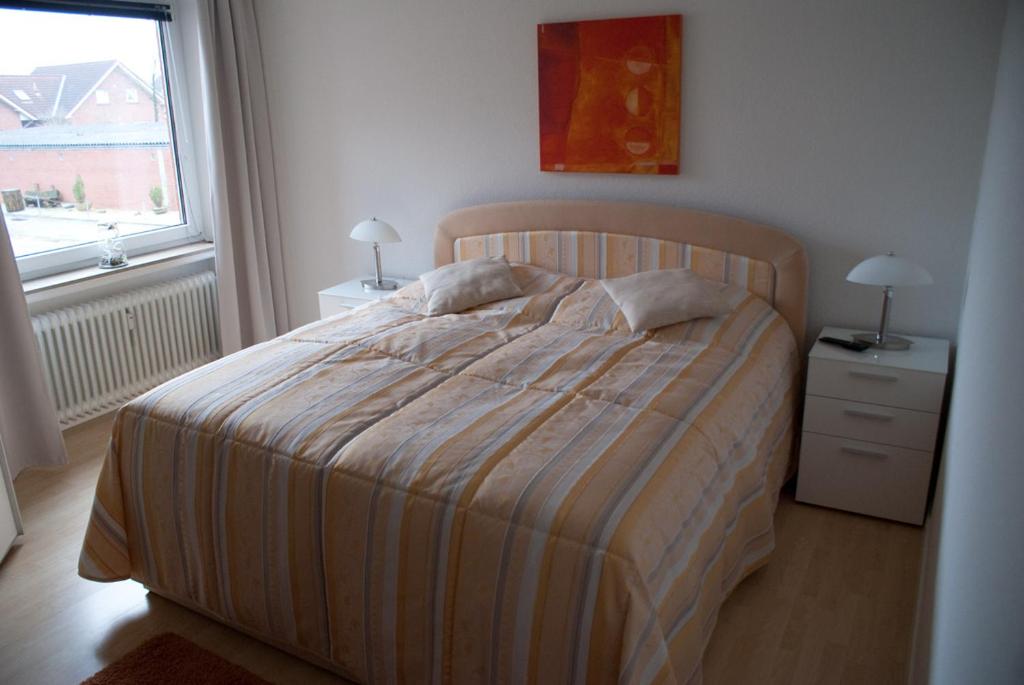 ein Schlafzimmer mit einem Bett mit einer gestreiften Decke und einem Fenster in der Unterkunft Aaltine 1 in Bad Bentheim