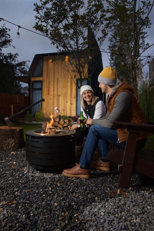 two people sitting on a bench next to a fire at Cabin Box Huasca in Huasca de Ocampo