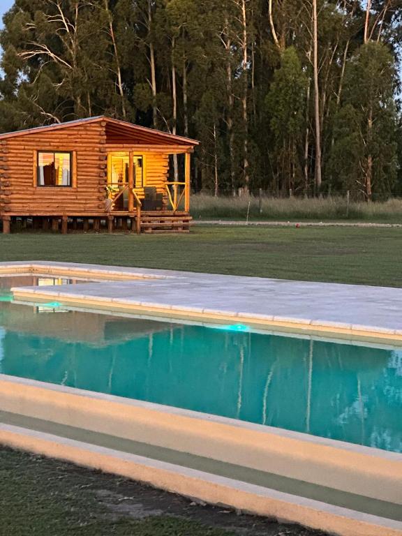 a log cabin with a swimming pool and a house at Cabañas Laguna de los Sauces in Azul