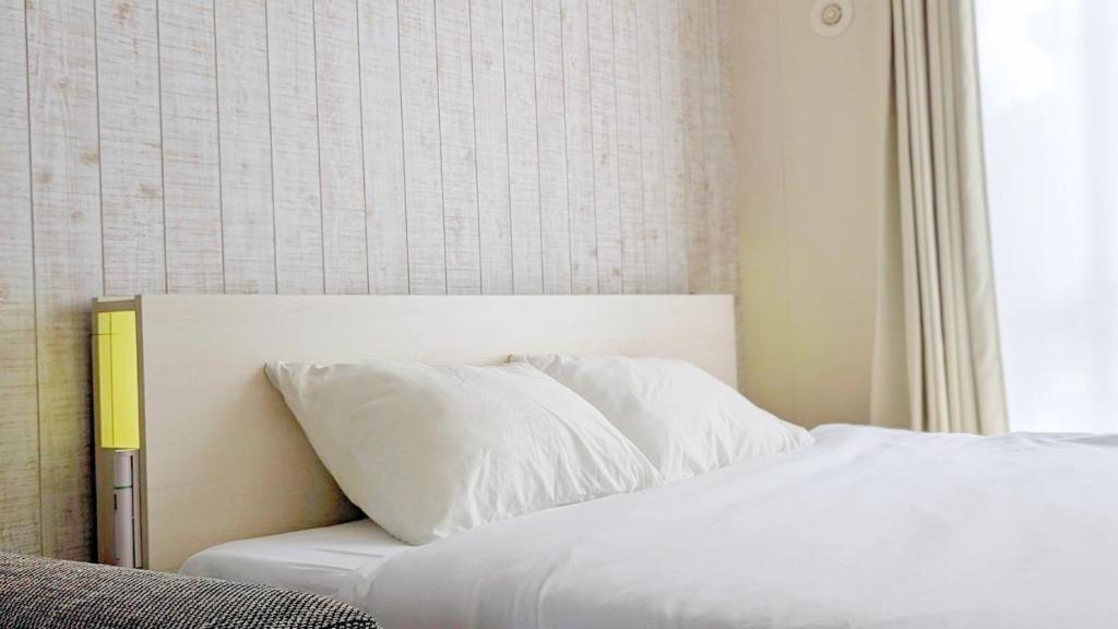 un lit avec des oreillers blancs assis à côté d'une fenêtre dans l'établissement Yonagunijima Hotel Munbu Stay Kukomae - Vacation STAY 87378v, à Sonai