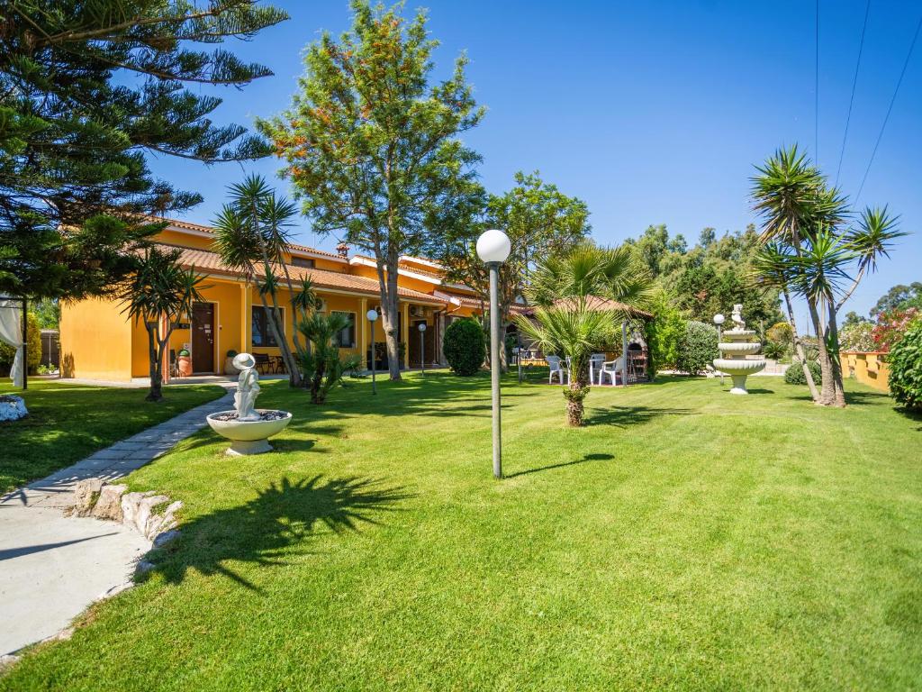 a park in front of a yellow building with a fountain at MEMO'S Affittacamere in Arborea