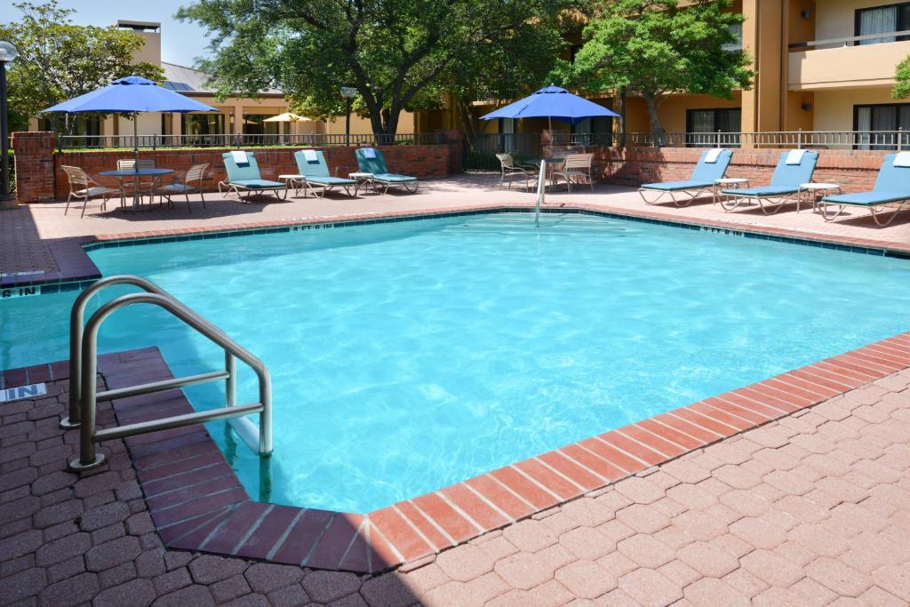 a large swimming pool with chairs and umbrellas at Courtyard Dallas Las Colinas in Irving