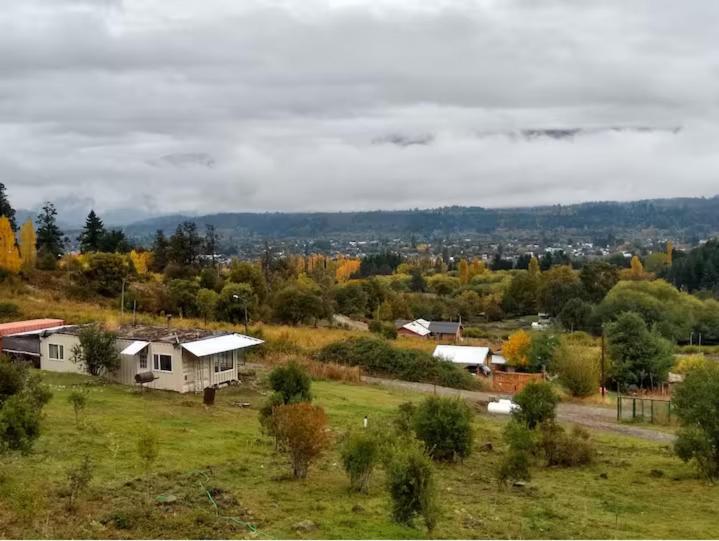 una casa en un campo con una ciudad en el fondo en Una Morada en la Montaña, en El Bolsón